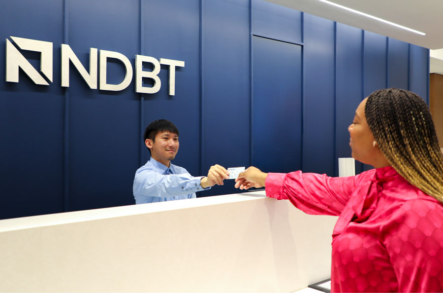 teller handing debit card to customer in the Dallas banking center