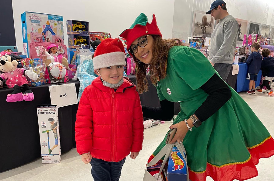 An elf helping a child select toys during NDBT Make a Wish Christmas event