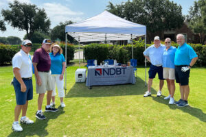NDBT professionals and movie actor Burton Gilliam alongside NDBT sponsor tent and table