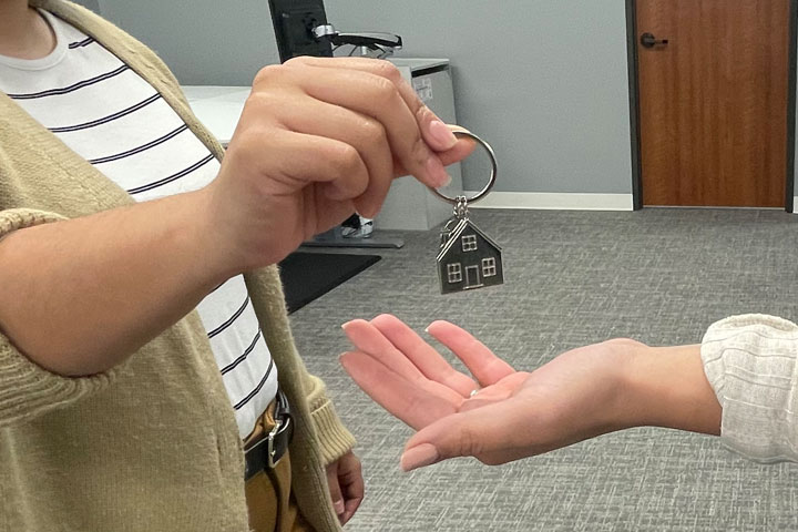 Person handing a house key-chain to another