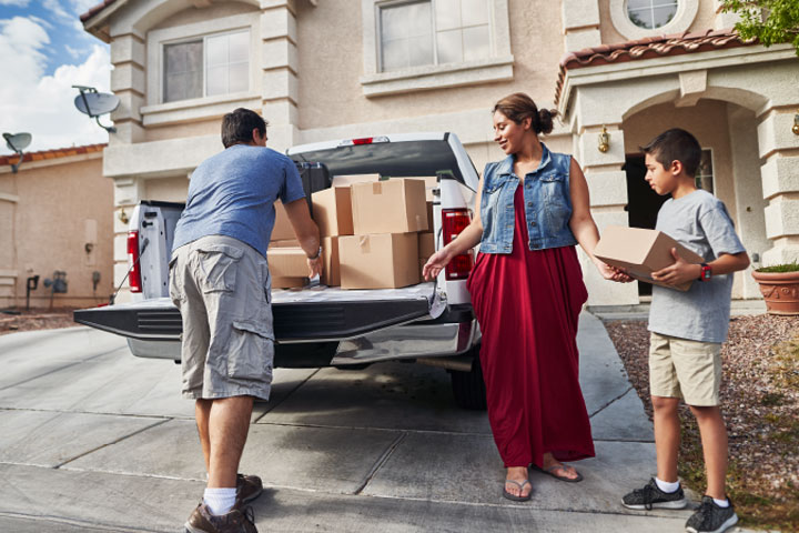 Hispanic family getting boxes from truck at new house
