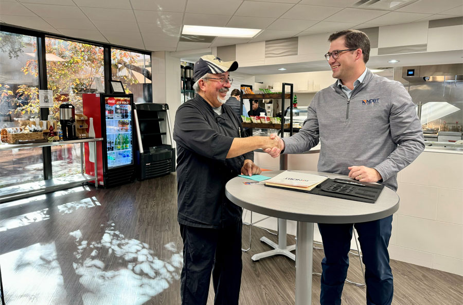 NDBT banker Sam Gunn shaking hands with business client in client's cafe