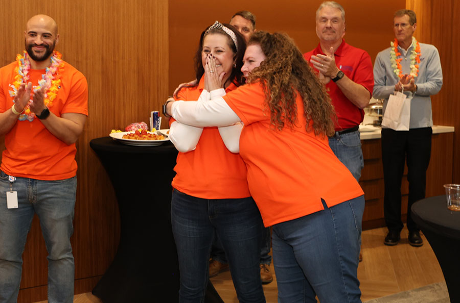 NDBT banker Michelle Mercado hugged by fellow banker upon winning volunteer of the year