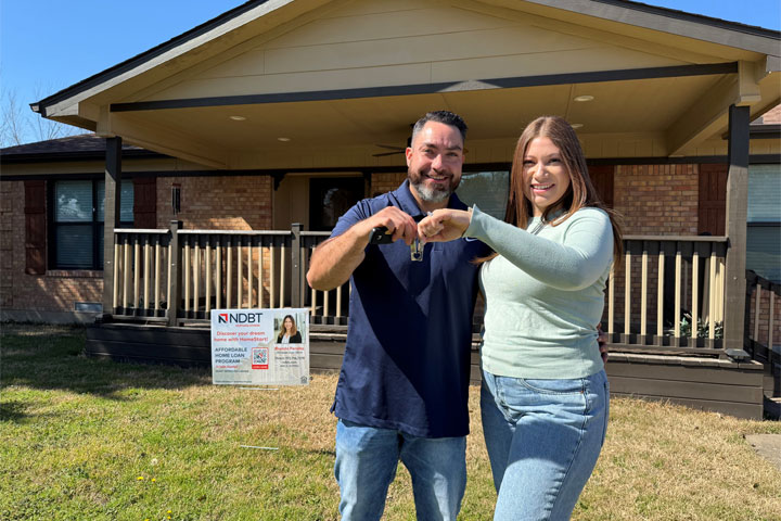 Couple holding keys outside home