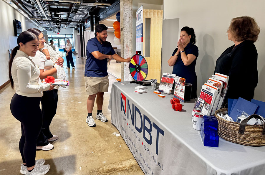 NDBT volunteers at table with participants spinning prize wheel