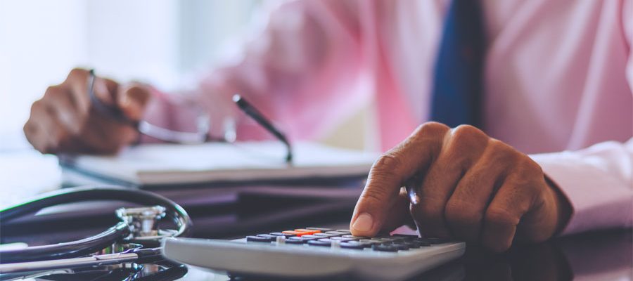 medical professional at a desk using a calculator